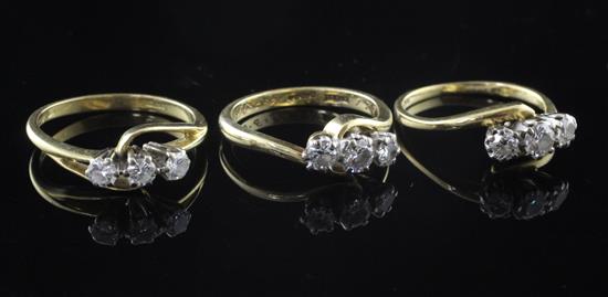 Three modern 18ct gold and three stone diamond rings, sizes N & K(2).